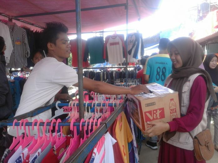 Pedagang sedang memberikan donasinya ke dalam kotak donasi melalui volunteer yang sedang menggalang dana untuk korban bencana Tsunami Selat Sunda. Kegiatan Berlangsung di Pasar Pagi kampus II UIN Jakarta pada 30 Desember 2018.